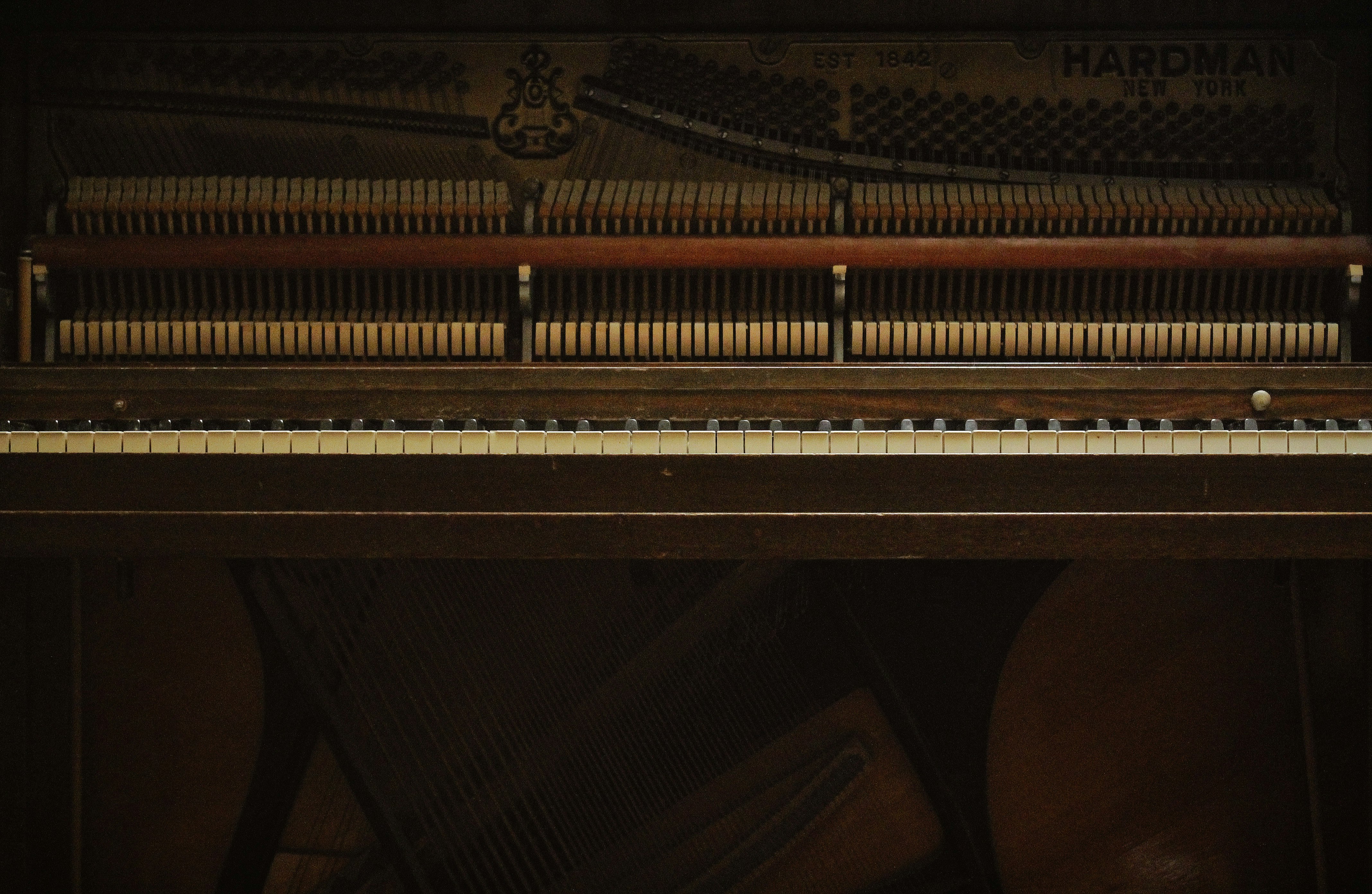 brown wooden upright piano with bench